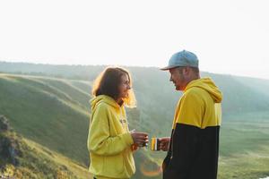 Young happy family couple travelers in casual outfits with tea in morning on beautiful view background. Local tourism, the weekend trip photo