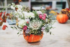 DIY autumn flower arrangement bouquet in pumpkin at the floristry studio photo