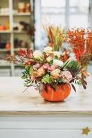 DIY autumn flower arrangement bouquet in pumpkin at the floristry studio photo