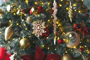 árbol de navidad decorado con juguetes dorados y rojos con las luces de fondo texturizado foto