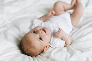 Cute baby girl 2-4 month on bed with white linen, natural tones, selective focus photo