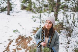 retrato de joven morena hermosa mujer con sombrero y poncho gris en el bosque de invierno foto