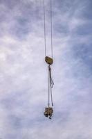 A hook of a crane with load at the blue sky with clouds as a background. Vertical view photo