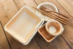 Natural eco-friendly food packaging disposable utensils with dish plate bowl cup and wooden fork spoon Eco friendly disposable tableware from palm leaf or betel nut , zero waste environment concept photo