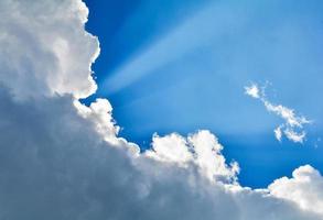 rayos de sol brillando con nubes y fondo de cielo azul foto