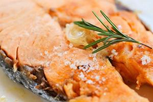 Salmon steak with herbs and spices rosemary on plate background - Close up cooked salmon fish fillet steak seafood photo