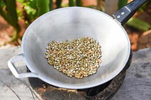 roasted coffee beans on hot pan in the mountain countryside - fresh raw coffee beans photo