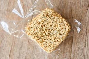 instant noodles in package on wooden background - dry food non perishable storage goods in kitchen home or for donations photo