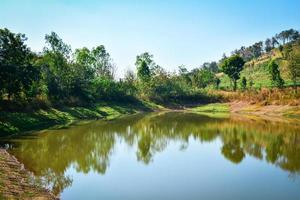 Pond on summer season forest with agricultural area and mountain background sunny day photo
