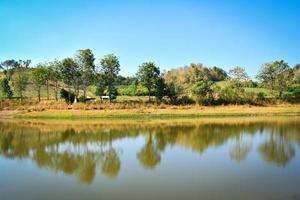 Pond on summer season forest with agricultural area and mountain background sunny day photo