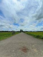 Long village road in Chandpur, Bangladesh. An empty cycle standing on the road side. photo