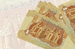 1 Egyptian pound bills lies in stack on background of big semi-transparent banknote. Abstract presentation of national currency photo