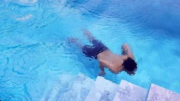 bangkok, tailandia-3 de enero de 2023 hombre borroso nadar en la piscina. la persona que conduce bajo el agua cerca de una escalera o escalera. actividad el fin de semana y viajar con relax. los asiáticos hacen ejercicio en el agua. foto