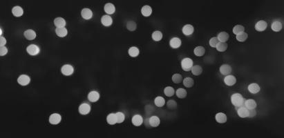 Blurred gray or grey Bokeh of light on dark or black background in monochrome style. Lighting blurry wallpaper. Festival or Celebration and Art of abstract concept. photo