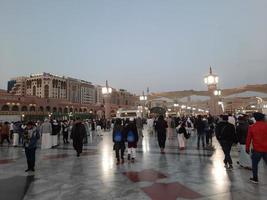 medina, arabia saudita, diciembre de 2022 - hermosa vista nocturna en masjid al-nabawi, los visitantes son vistos en las luces de la mezquita en las instalaciones de la mezquita. foto