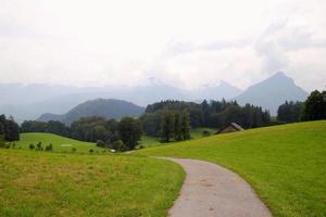viaje a sankt-wolfgang, austria. el camino entre campos con las casas y las montañas al fondo. foto