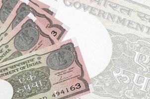 Los billetes de 1 rupia india se encuentran apilados en el fondo de un gran billete semitransparente. fondo de negocios abstracto foto