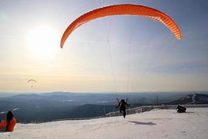 viajar a sheregesh, rusia. el parapente está despegando cerca de las montañas. paisaje de invierno foto