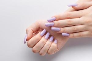 manos de una chica con una manicura violeta suave sobre un fondo blanco.