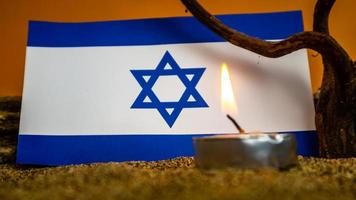 bandera israelí y velas encendidas frente a ella, día de la memoria del holocausto foto