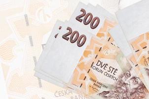 200 Czech korun bills lies in stack on background of big semi-transparent banknote. Abstract presentation of national currency photo