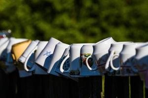 a row of coffee mugs stacked on the fence photo