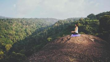 Asian women relax in the holiday. Play if yoga. On the Moutain rock cliff. Nature of mountain forests in Thailand photo