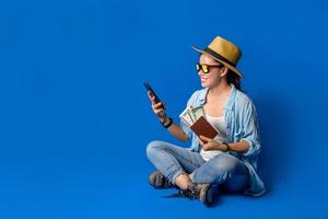 Young asian traveler happy in blue shirt holding passport with holding mobile phones in the hand. concept travel with equipment for travelers Vacation, on Blue color background. Travel relax photo