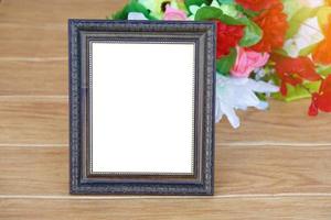 Photo frame on wooden floor, decorated with flowers behind. Copy space for adding text or photos.  Concept, Proud, memories and nostalgia. Exhibition, art gallory. Photograpy.