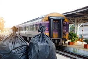 Closeup two black plastic bags that contain garbage inside at the railway station in the evening light. Concept, garbage or rubbish from travelling. Enviromental problems photo