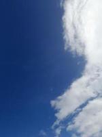 White clouds in the blue sky. Heaven and infinity. Beautiful bright blue background. Light cloudy, good weather. Curly clouds on a sunny day. photo