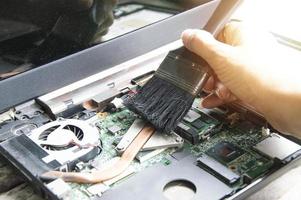 technician using brush Clean dusty notebooks. photo