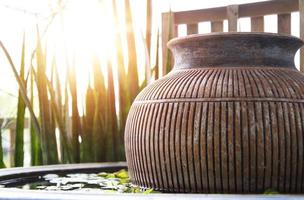 The evening sun shines on the water basin where the jar is placed inside. photo