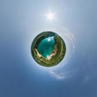 green tiny planet in blue sky with beautiful clouds. Transformation of spherical panorama 360 degrees. Spherical abstract aerial view. Curvature of space. photo