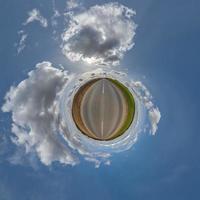 tiny planet in blue overcast sky with beautiful clouds with transformation of spherical panorama 360 degrees. Spherical abstract aerial view. Curvature of space. photo