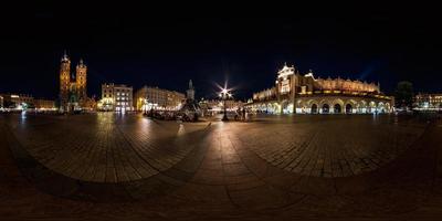 panorama nocturno completo de 360 en la plaza del mercado principal en el centro del casco antiguo con edificios históricos, templos y ayuntamiento con muchos turistas en proyección equirectangular foto