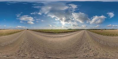 full hdri 360 panorama on no traffic gravel road among fields with overcast sky and white fluffy clouds in equirectangular seamless spherical projection,can be used as replacement for sky in panoramas photo