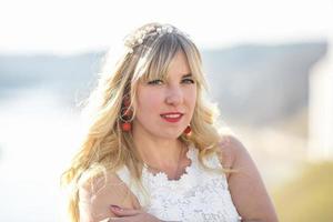 Outdoor close up portrait beautiful blonde girl with youth and skin care attractive looking at camera in white dress. Light key photo