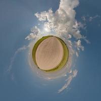 tiny planet in blue overcast sky with beautiful clouds with transformation of spherical panorama 360 degrees. Spherical abstract aerial view. Curvature of space. photo