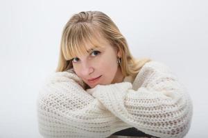 primer plano retrato de chica rubia modelo en suéter de lana blanca sobre fondo blanco en estudio foto
