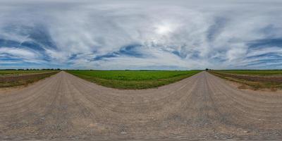 vista panorámica esférica completa hdri 360 sin tráfico en camino de grava sin tráfico entre campos con cielo nublado y nubes blancas en proyección equirectangular, puede usarse como reemplazo del cielo en panoramas foto