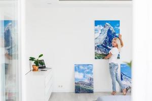 mujer joven cuelga la imagen de arte en la pared en casa foto