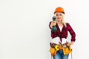 mujer trabajadora en casco con herramientas sosteniendo un taladro foto