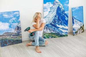 woman hangs photo canvas on wall