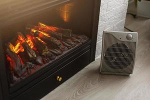 Heating radiator and a fireplace nearby in a white room with laminated wooden floor photo
