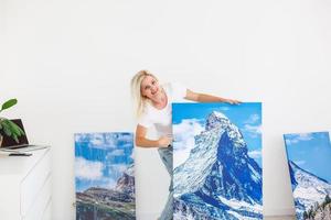 woman hangs photo canvas on wall