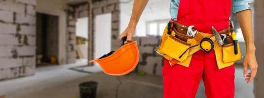 retrato de un alegre joven trabajador que lleva casco sobre fondo blanco foto