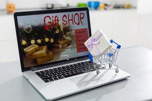 Shopping cart with gift box on the keyboard of computer. photo