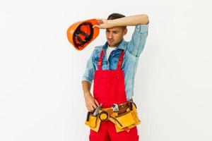 retrato de un alegre joven trabajador que lleva casco sobre fondo blanco foto