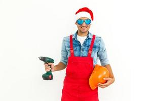 The guy, in uniform and Santa's hat, holds a drilland. Isolated on white background. photo